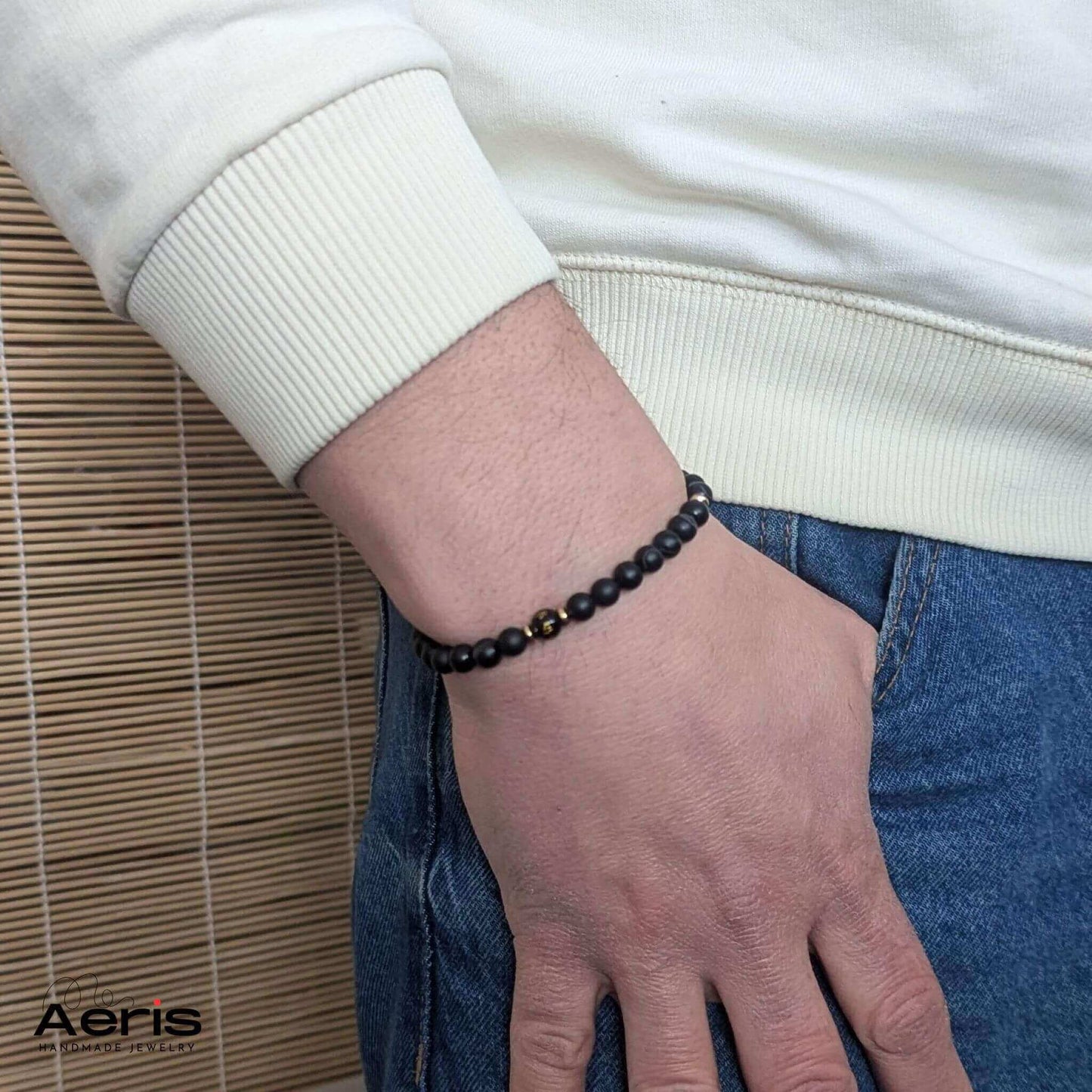 Bratara handmade cu mantra gravata si margele negre, pe mana