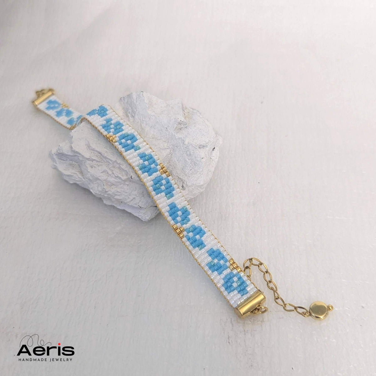 Bratara tesuta din margele Miyuki Delica, cu flori bleu pe fundal de culoare alba
