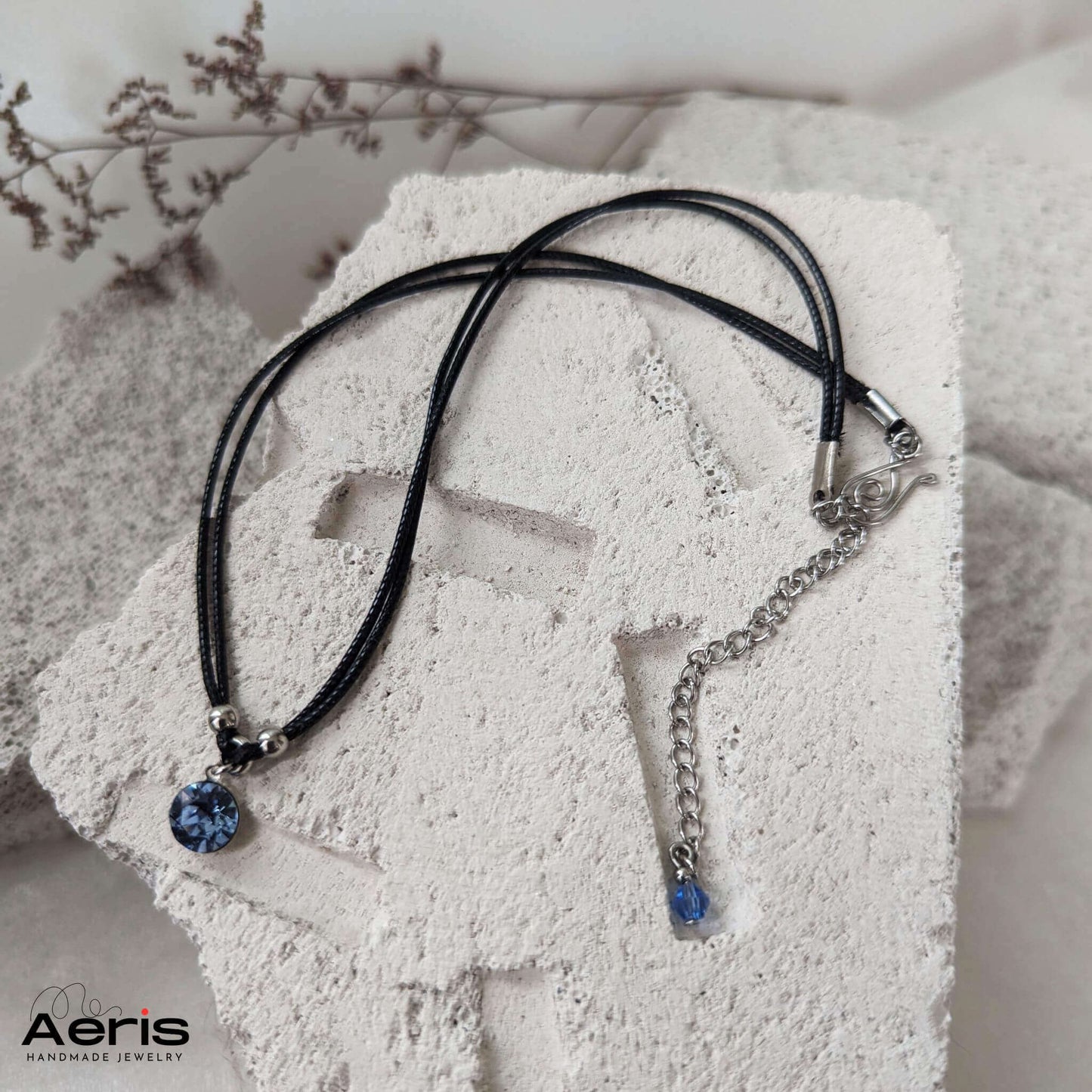 Choker negru minimalist asezat pe o placa din beton