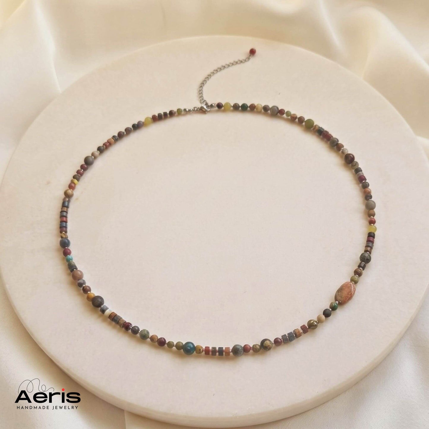 Clier handmade cu pietre semipretioase colorate, expus pe un disc din ceramica mata