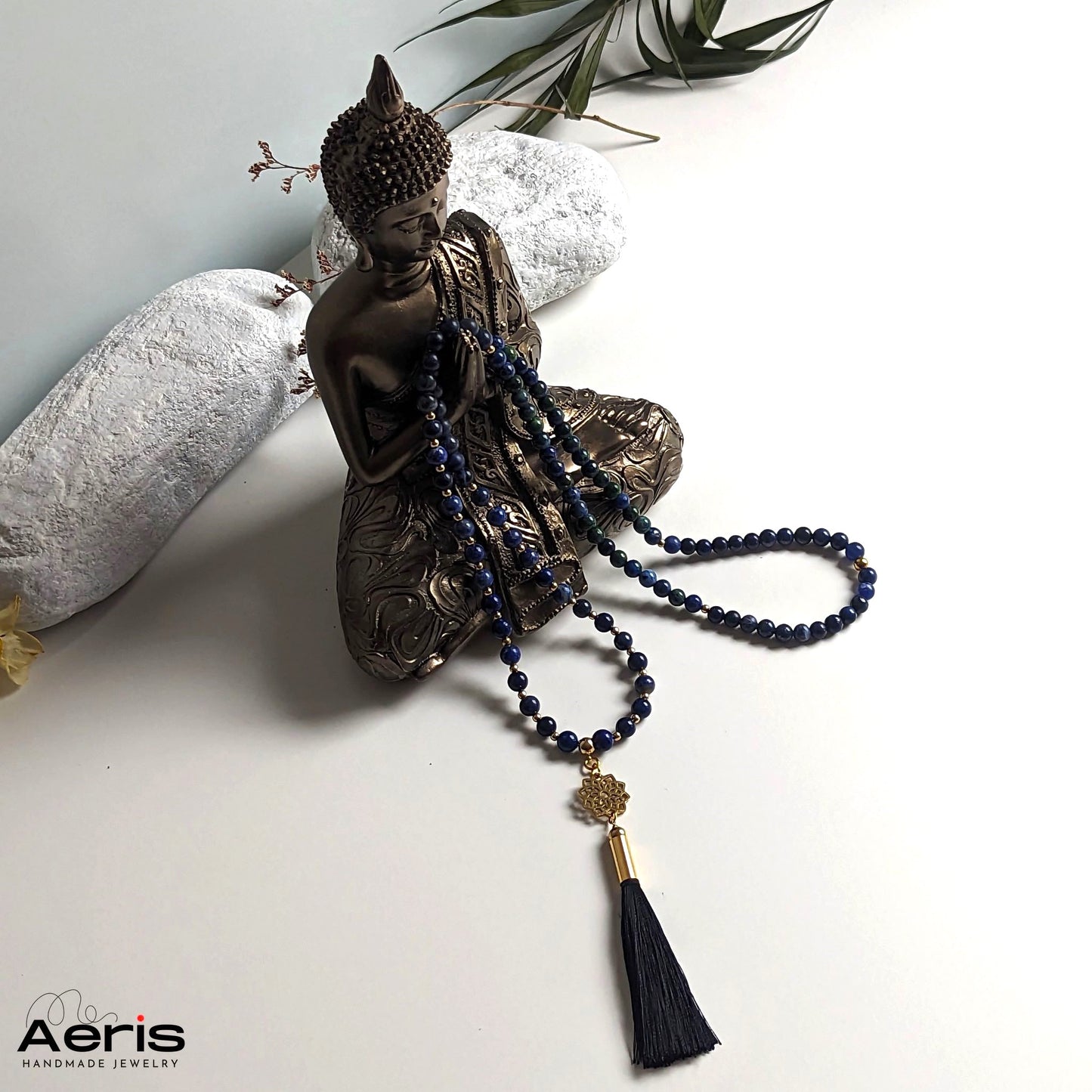 Colier mala cu mandala aurie si ciucure din matase negru, langa statuia lui Buddha