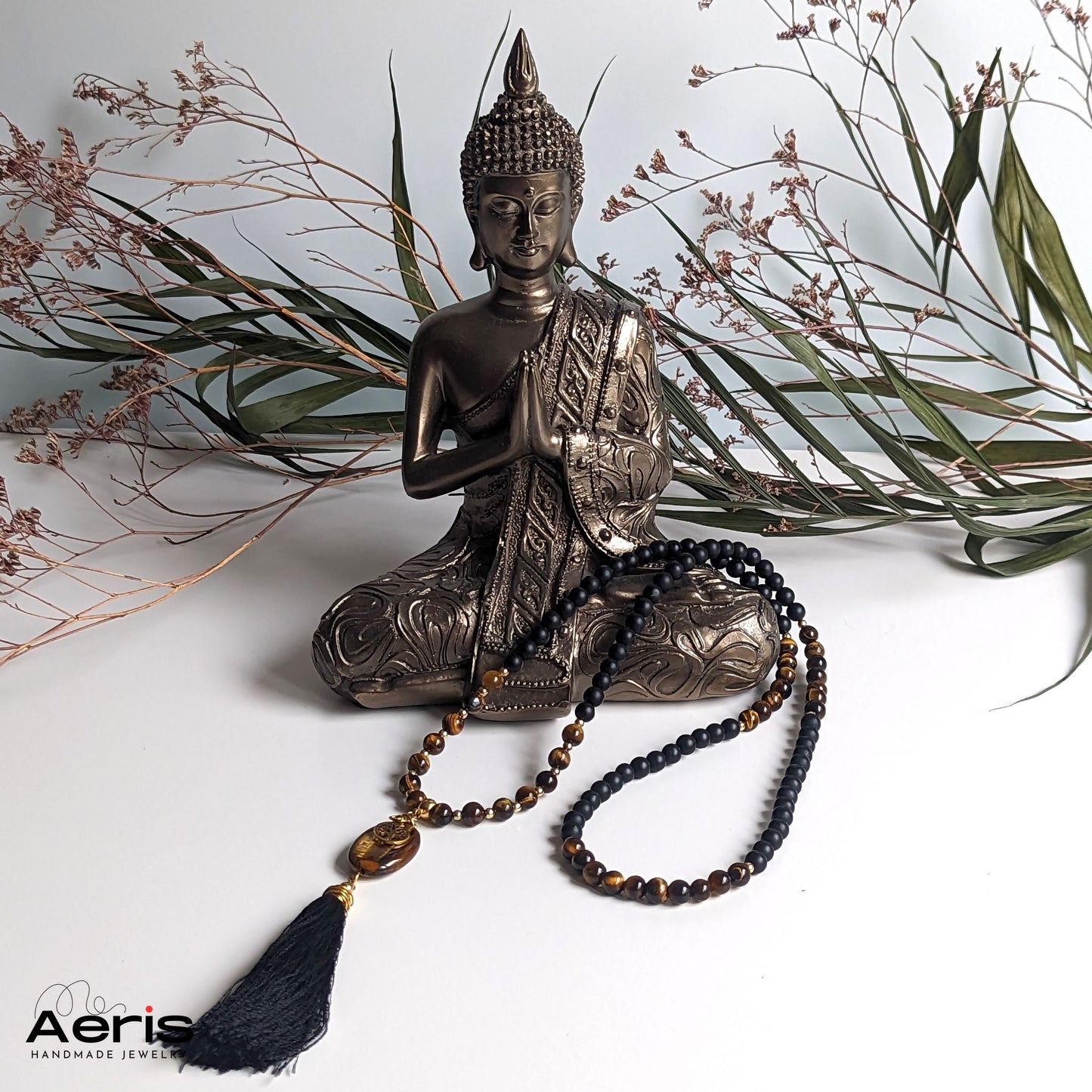 Colier cu copacul vietii asezat langa o statuie a lui Buddha