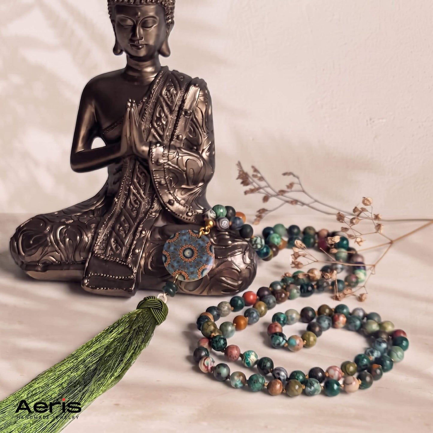 Colier mala cu pietre naturale in nuante verzi, alaturi de o statuie a lui Budha