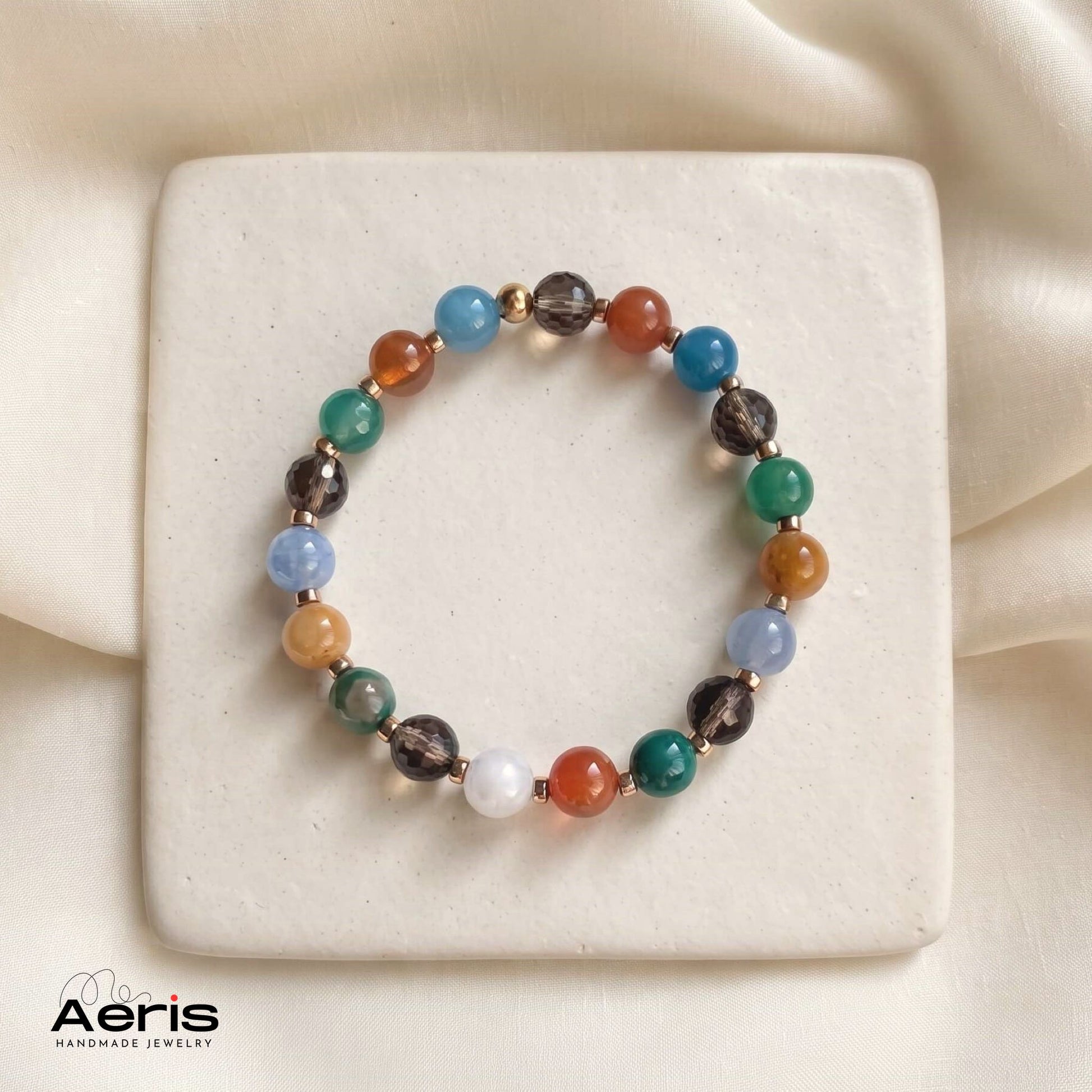 Bratara handmade de dama, cu agate multicolore si cuart fumuriu, prezentata pe un suport ceramic patrat