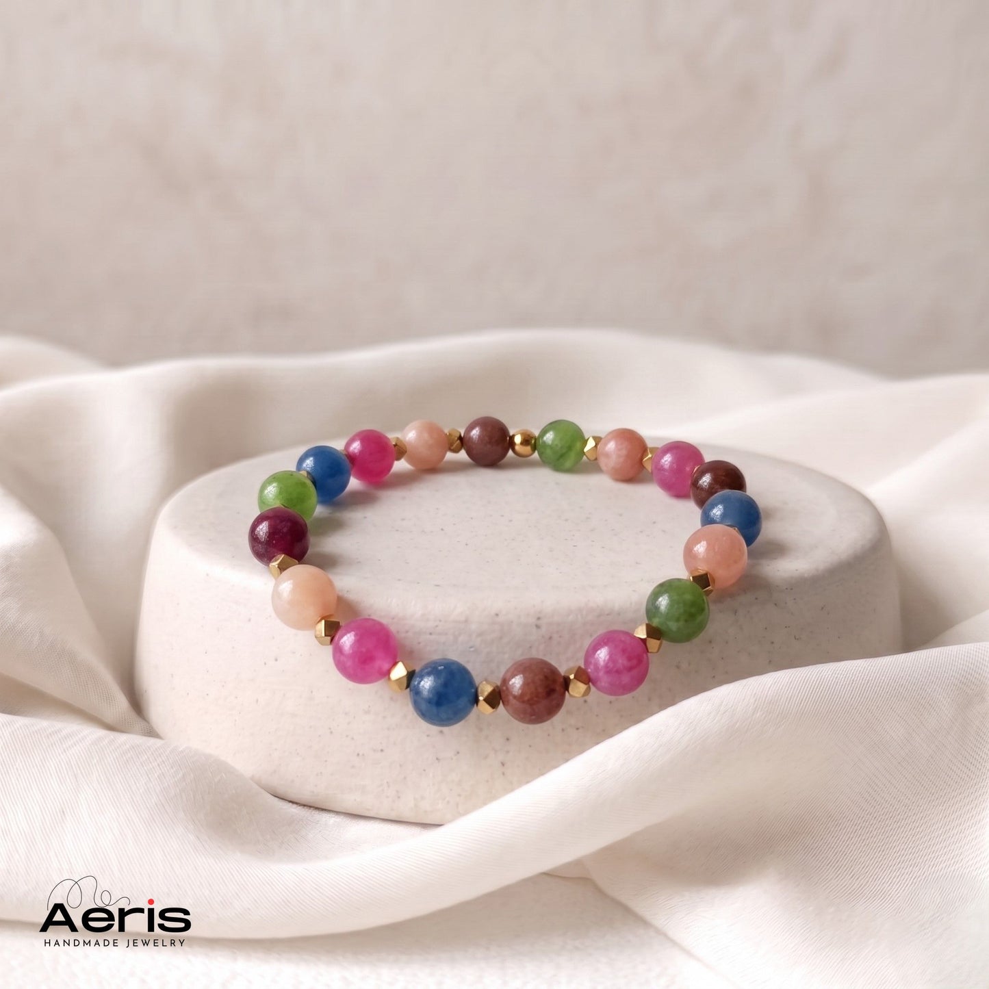 Bratara handmade multicolora din margele semipretioase, expusa pe un suport rotund din ceramica