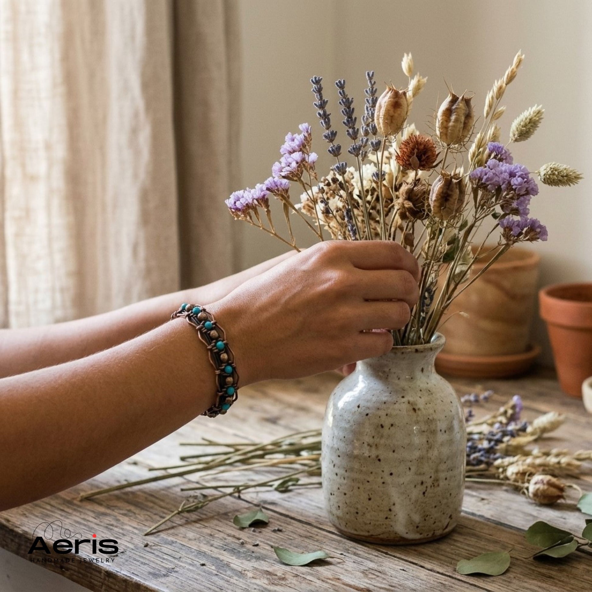 Femeie aranjand niste flori uscate intr-o vaza ceramica si purtand bratara handmade din cupru si turcoaz