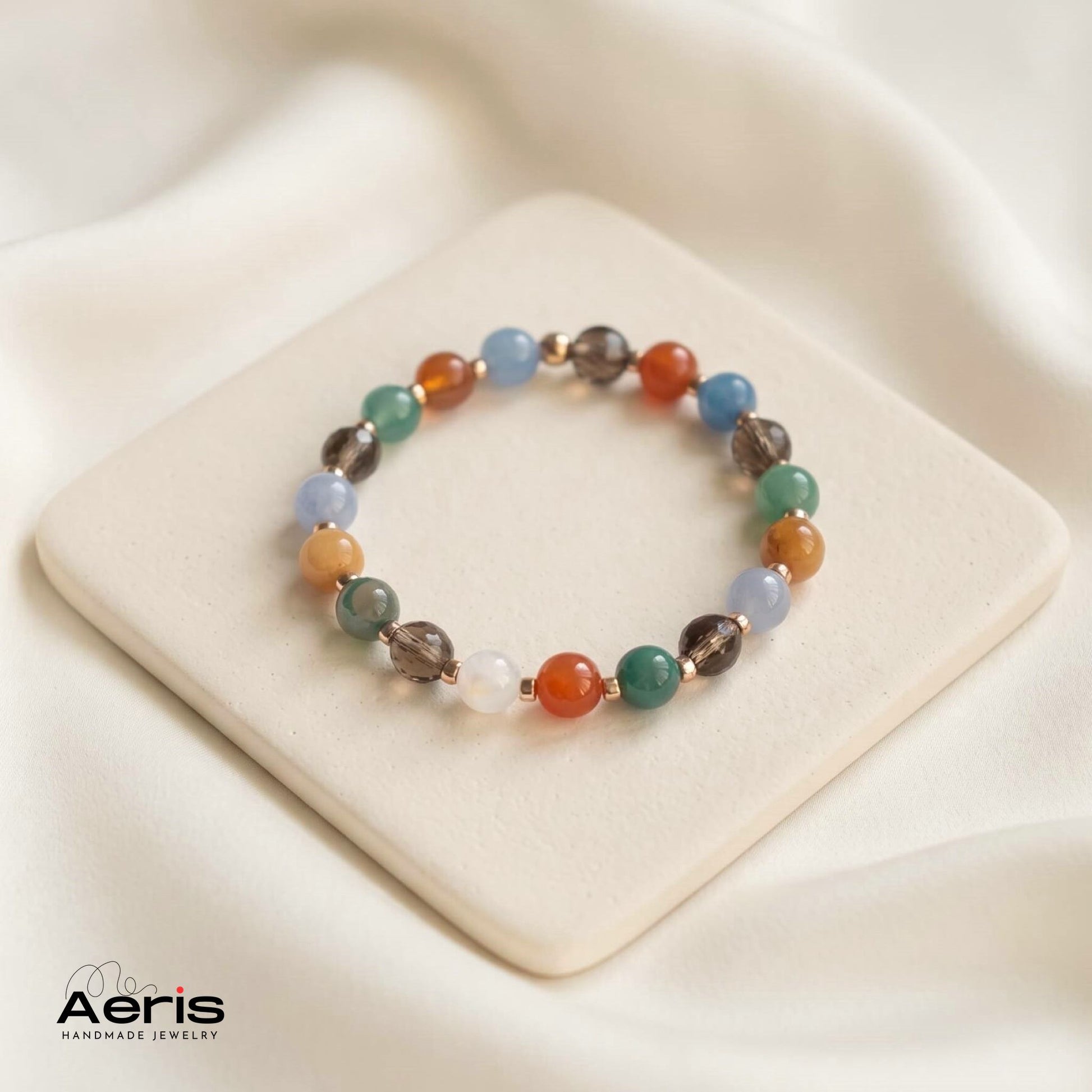 Bratara multicolora cu agate si cuart fumuriu, asezata pe un suport ceramic patrat