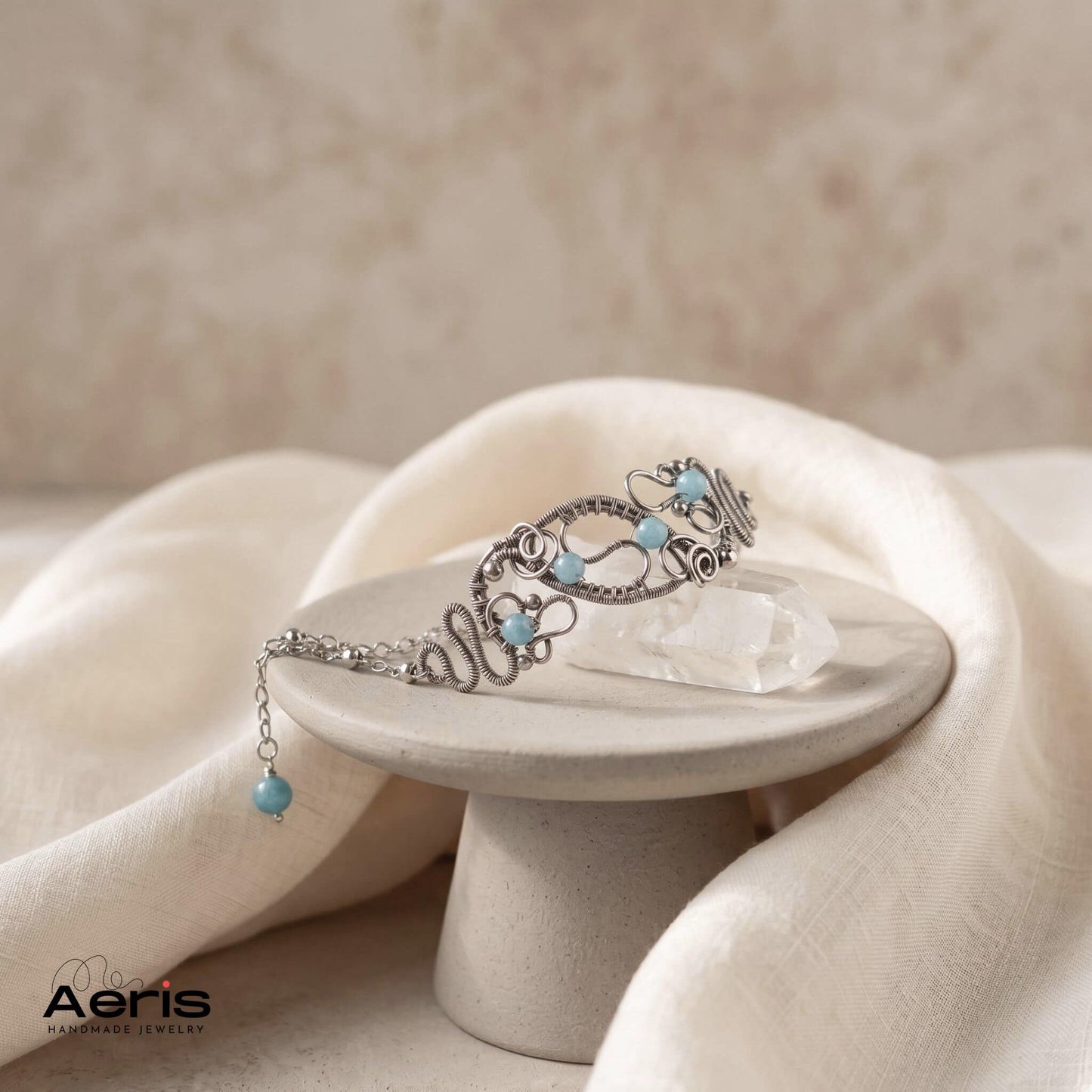 Bratara originala lucrata in tehnica wire wrapping din sarma de inox si angelit, prezentata pe un piedestal ceramic