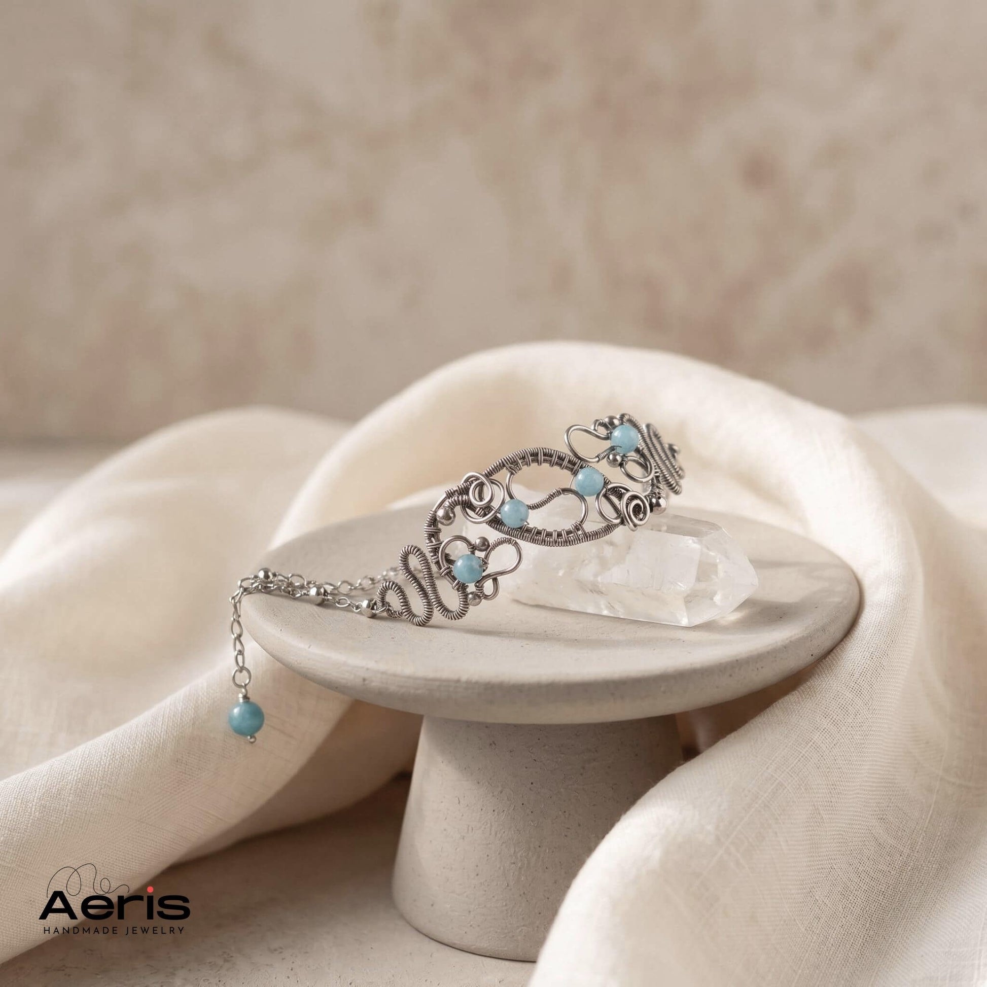Bratara originala lucrata in tehnica wire wrapping din sarma de inox si angelit, prezentata pe un piedestal ceramic