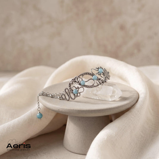 Bratara originala lucrata in tehnica wire wrapping din sarma de inox si angelit, prezentata pe un piedestal ceramic