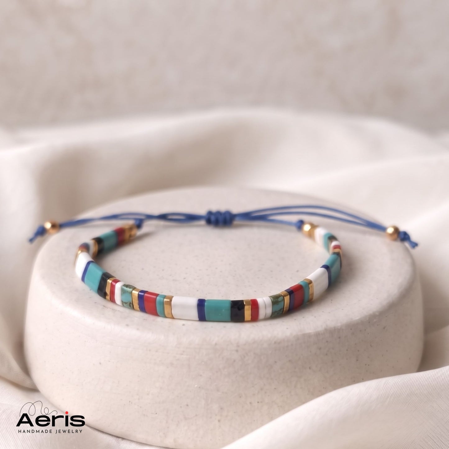 Bratara handmade din margele patrate multicolore, asezata pe un suport ceramic