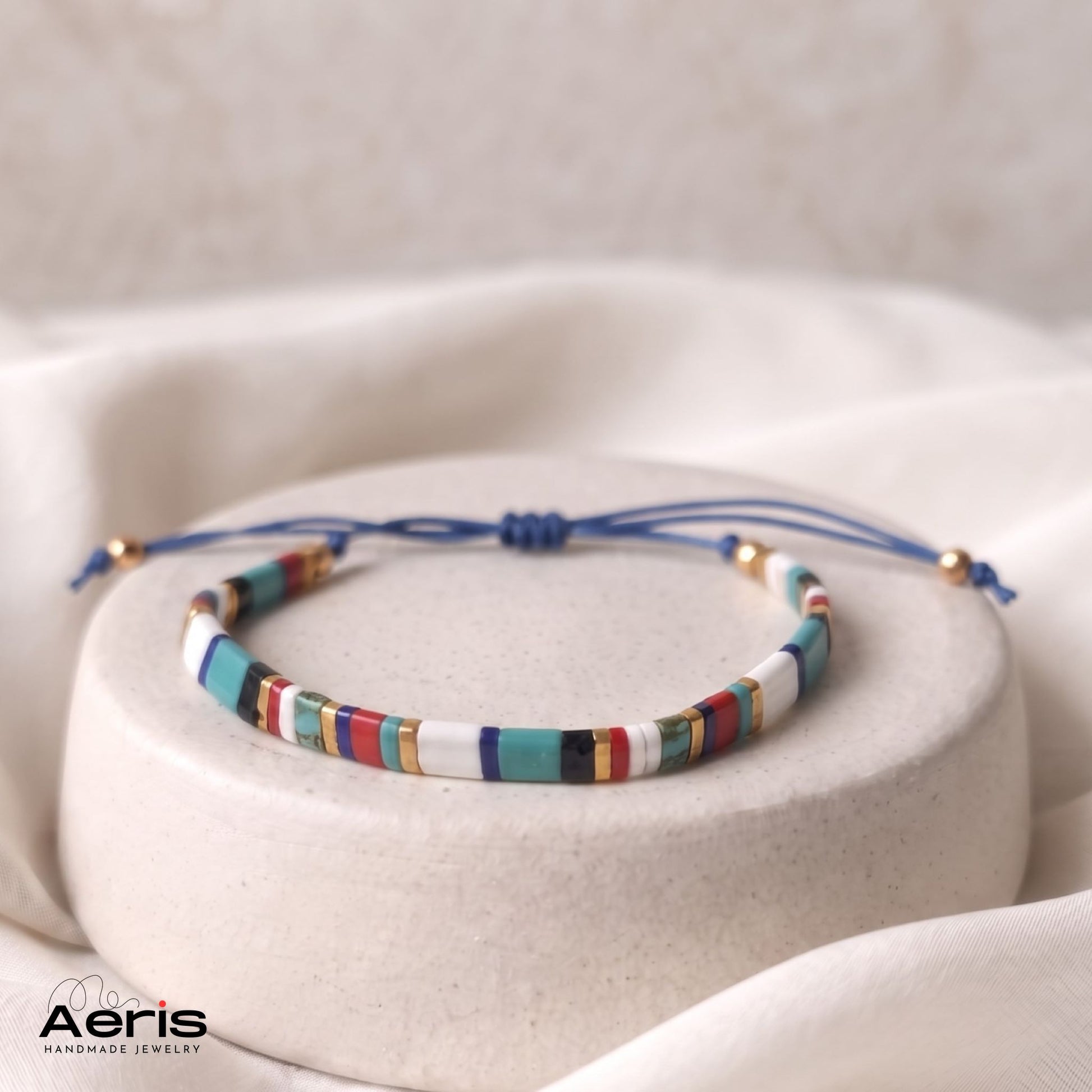 Bratara handmade din margele patrate multicolore, asezata pe un suport ceramic