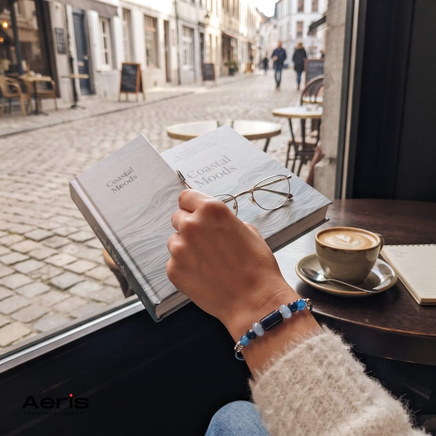 Bratara cu agate albastre purtata de o femeie in tinuta casual care isi savureaza cafeaua intr-un cofee shop