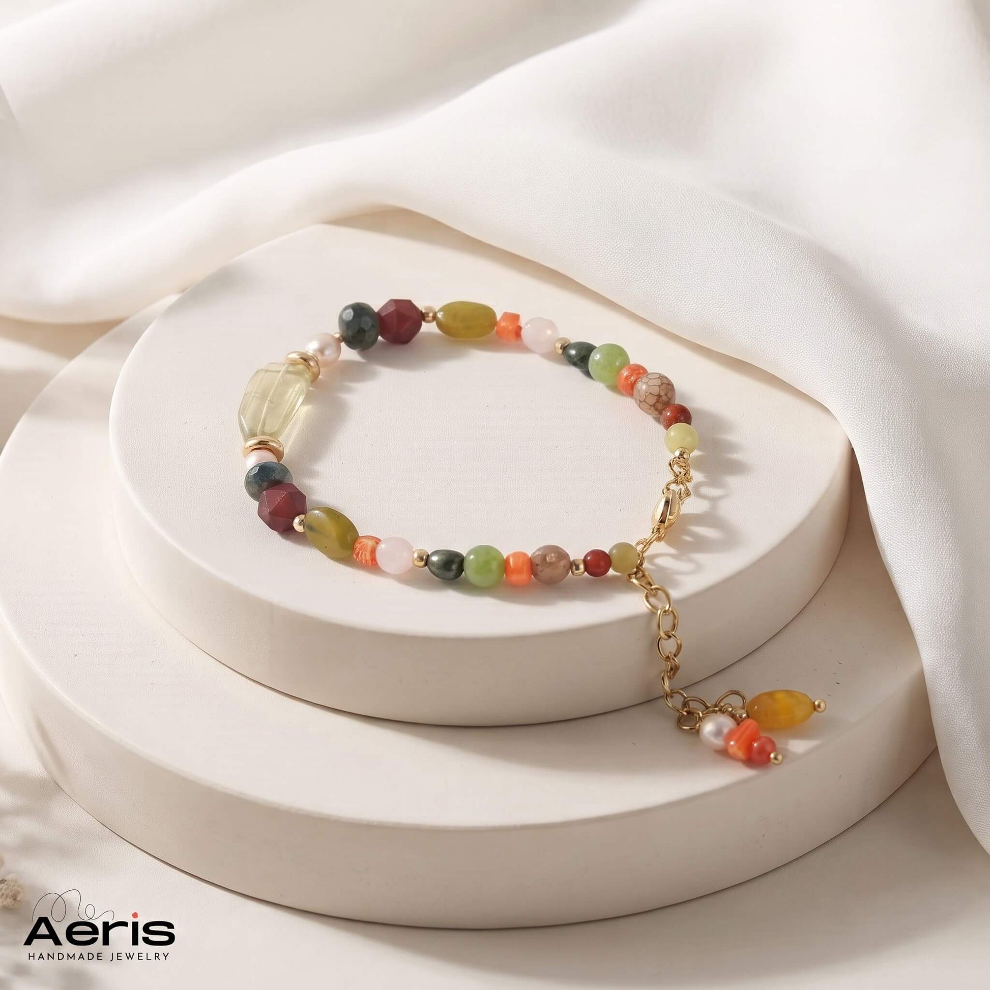 Bratara handmade din margele semipretioase, cu charm si accesorii din inox auriu, expusa pe un suport ceramic