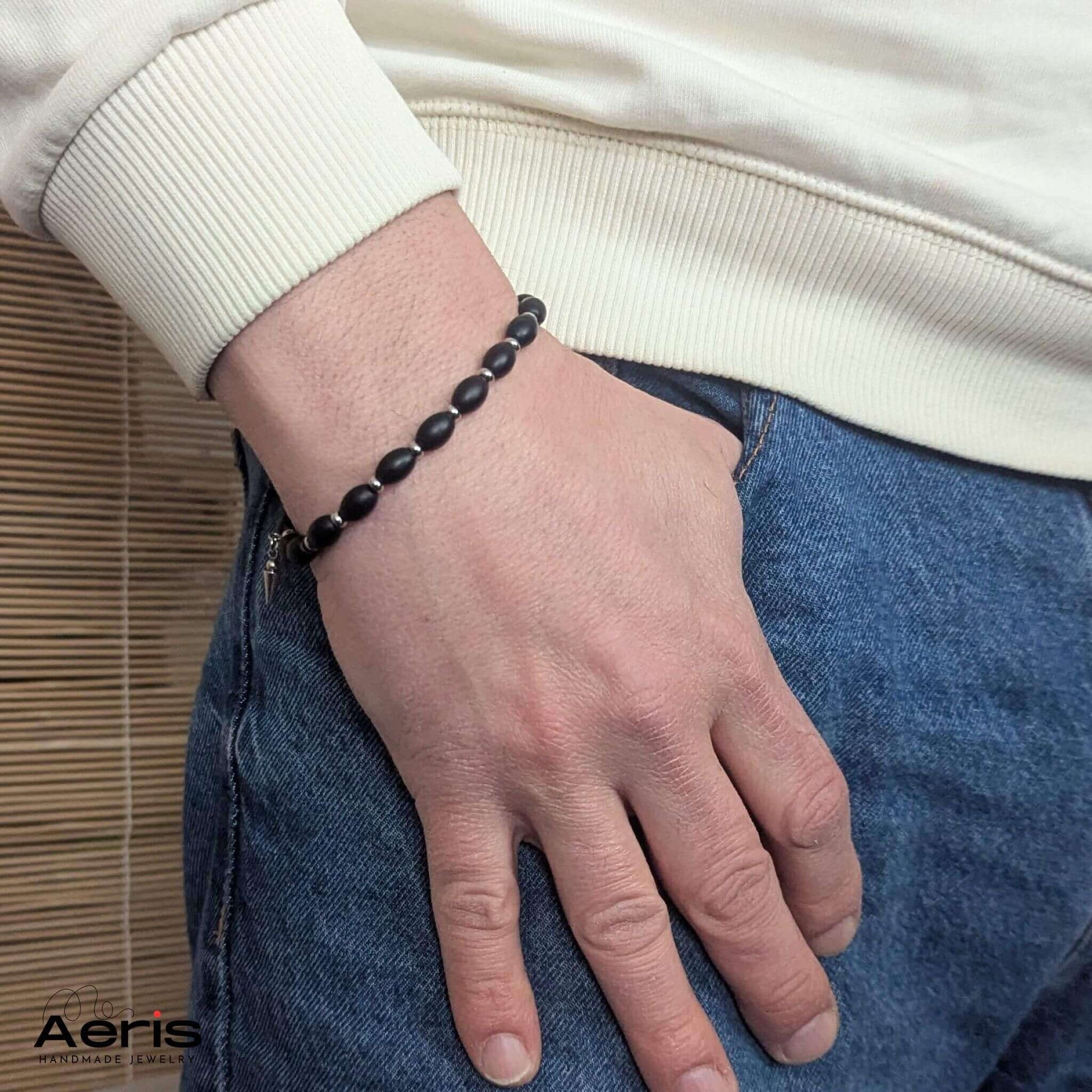 Bratara handmade barbateasca cu margele ovale din onix negru si charm, pe mana