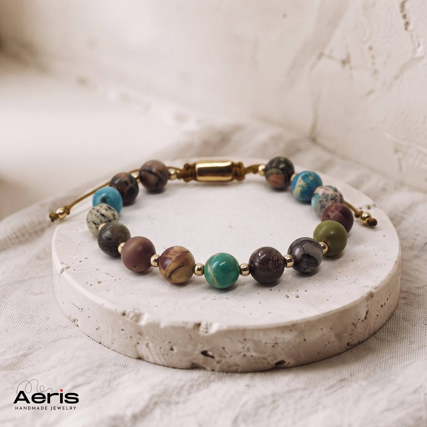 Bratara handmade pe snur, cu margele din jasp, expusa pe un suport rotund din travertin