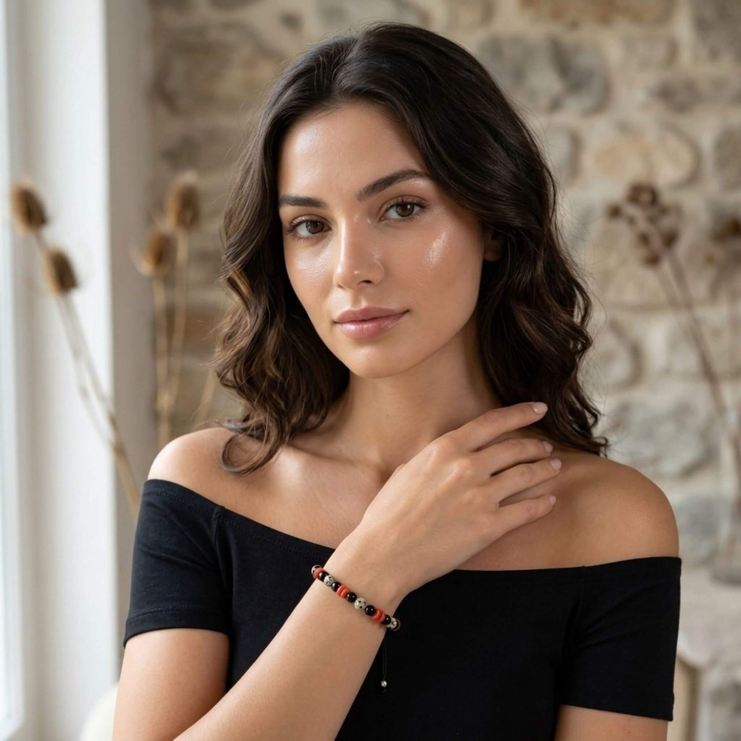 Tanara eleganta in rochie neagra, purtand pe incheietura mainii bratara cu pietre semipretioase multicolore