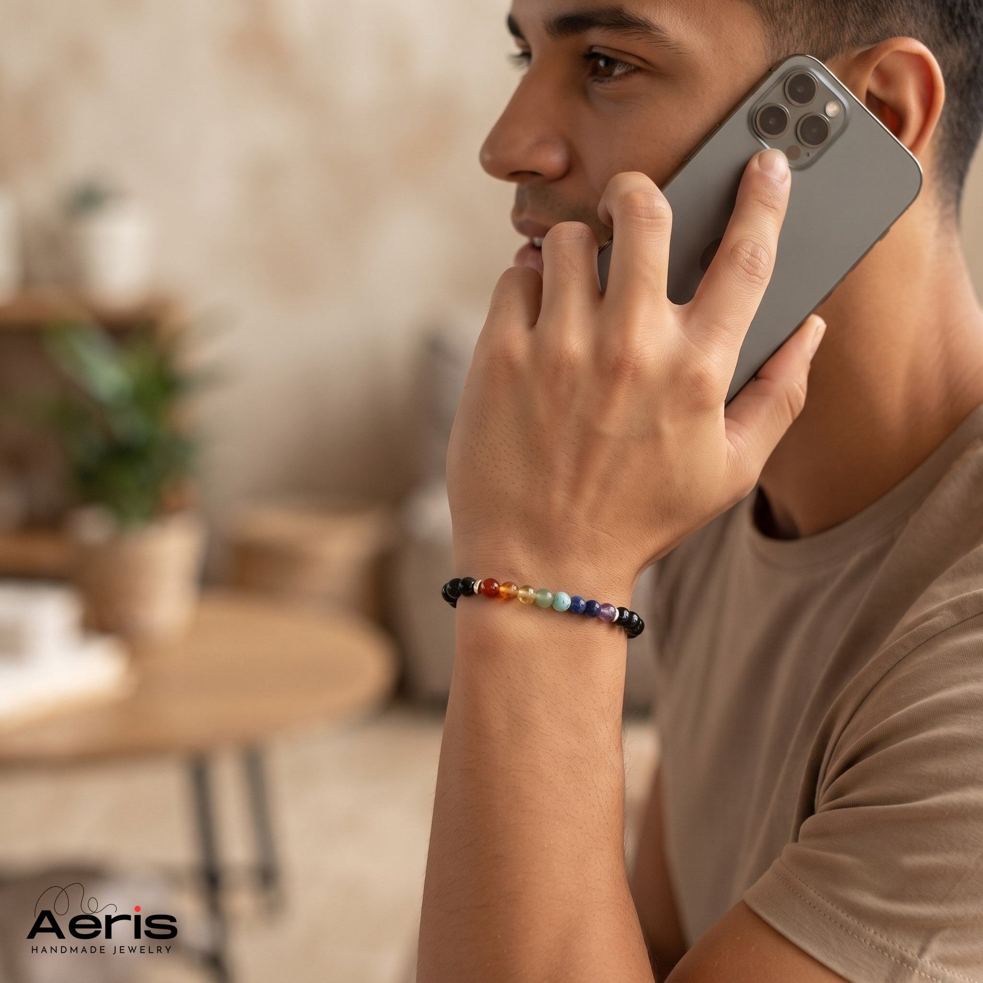 Barbat care vorbeste la telefon si are pe incheietura mainii o bratara spirituala cu margele colorate in culorile celor 7 chakre