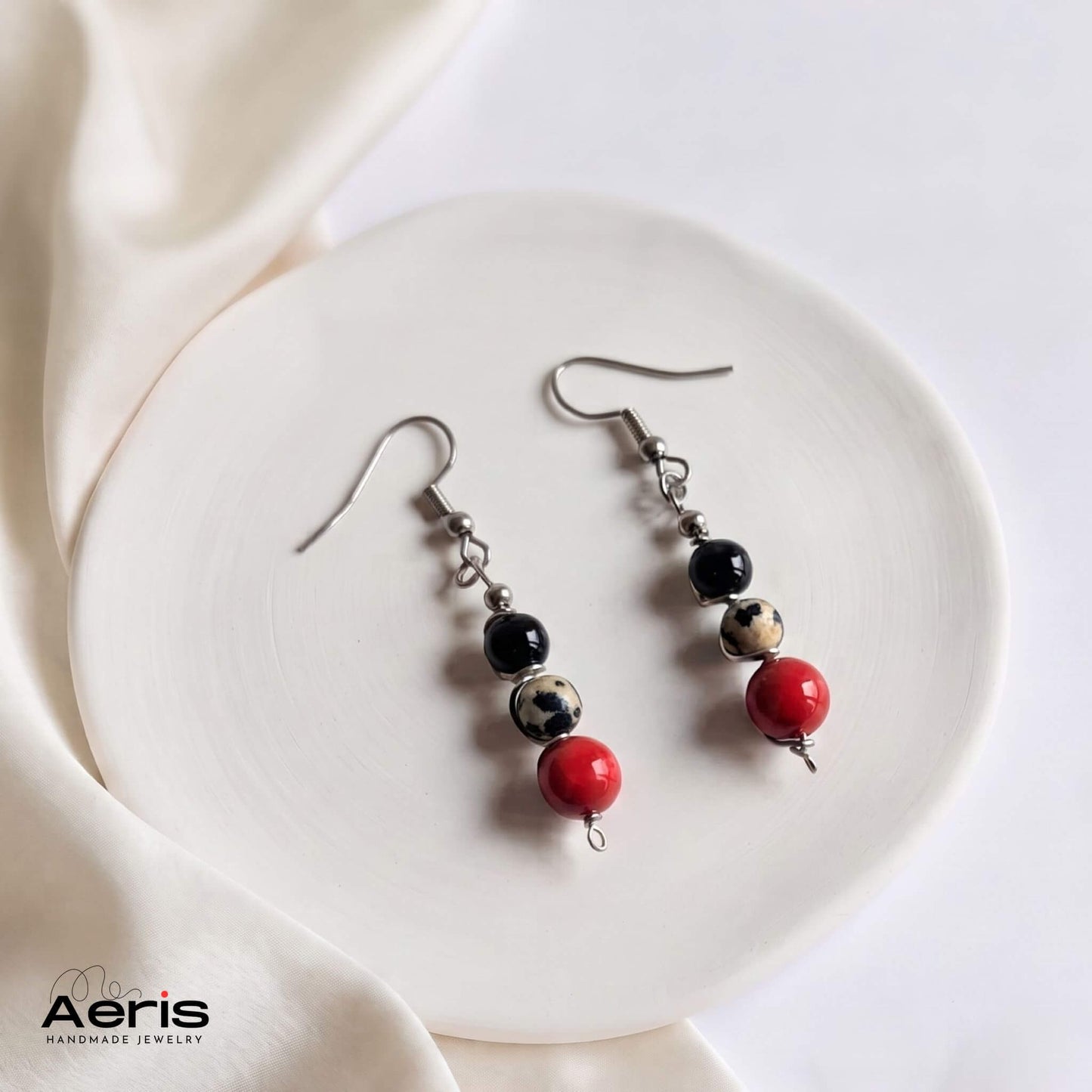 Cercei handmade cu carlig din inox si margele rosii, albe si negre, asezati pe un disc din ceramica mata