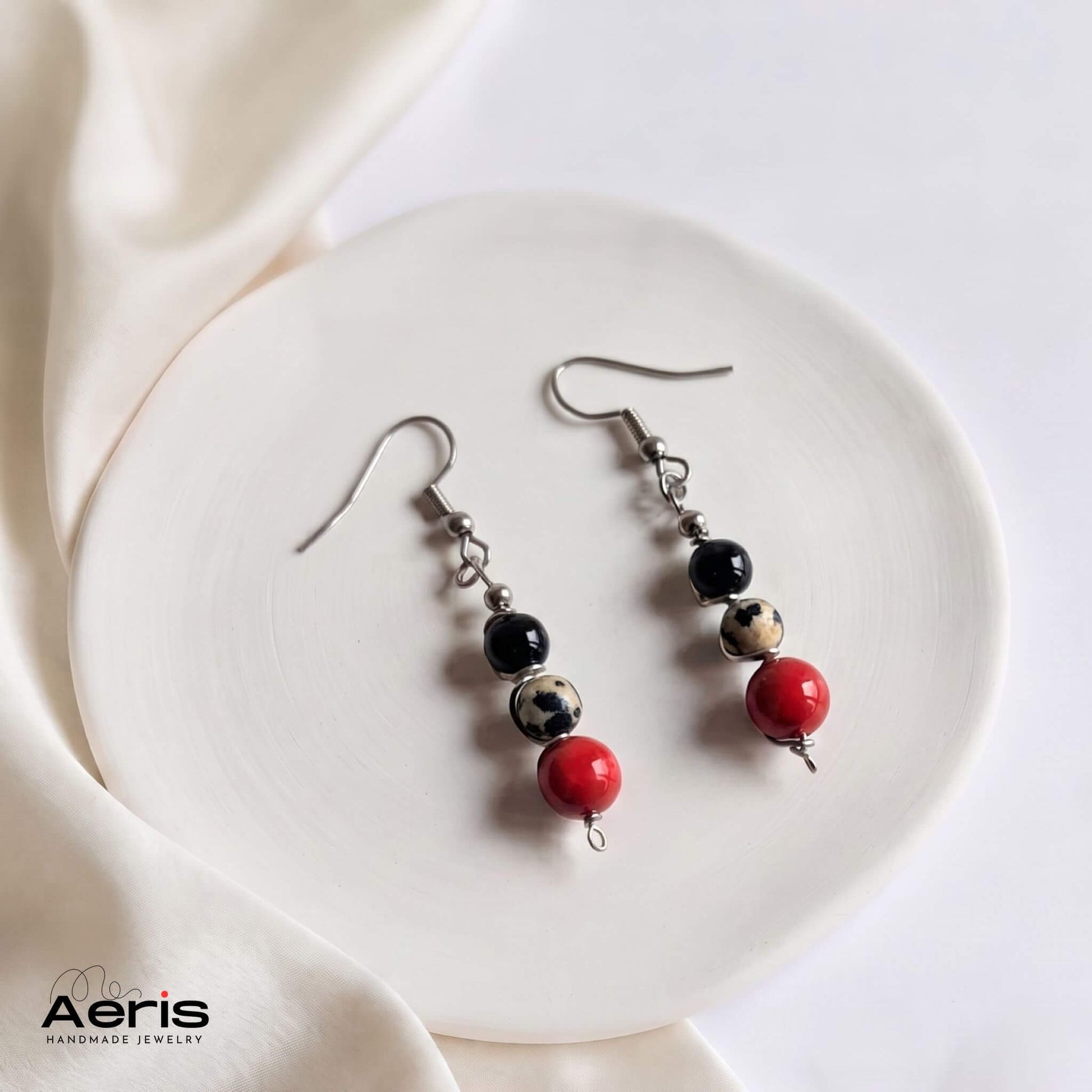 Cercei handmade cu carlig din inox si margele rosii, albe si negre, asezati pe un disc din ceramica mata