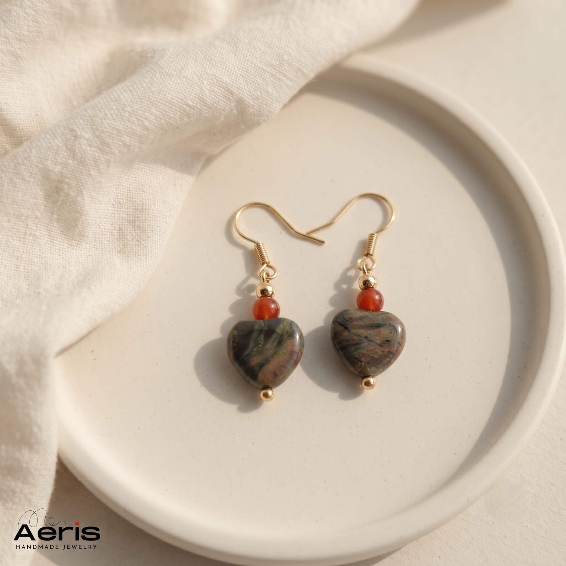 Cercei handmade cu margele semipretioase in forma de inima si tortite carlig din inox auriu. Prezentati pe un disc rotund din ceramica mata.