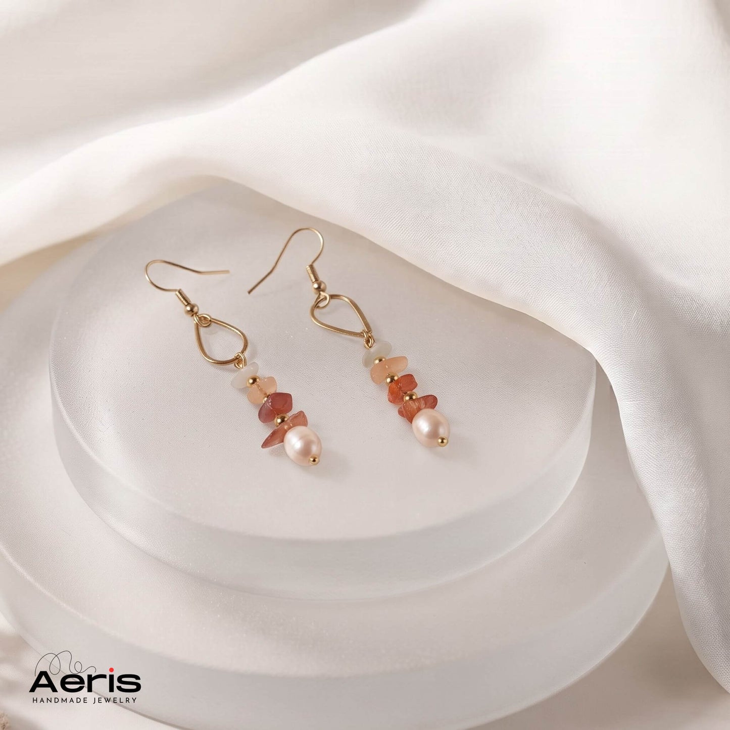 Cercei cu chipsuri, perle si accesorii din inox auriu, prezentati pe un suport de sticla mata