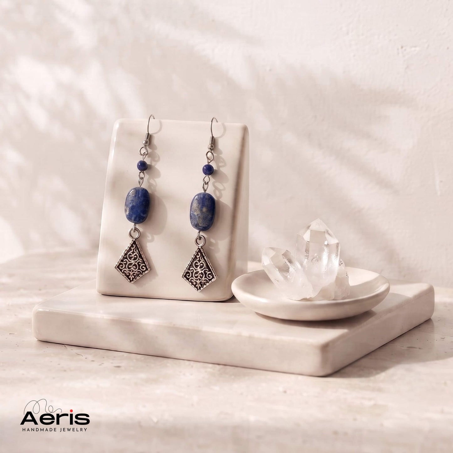 Cercei pendul, lungi, cu lapis lazuli si elemente metalice vintage, prezentati pe suport ceramic