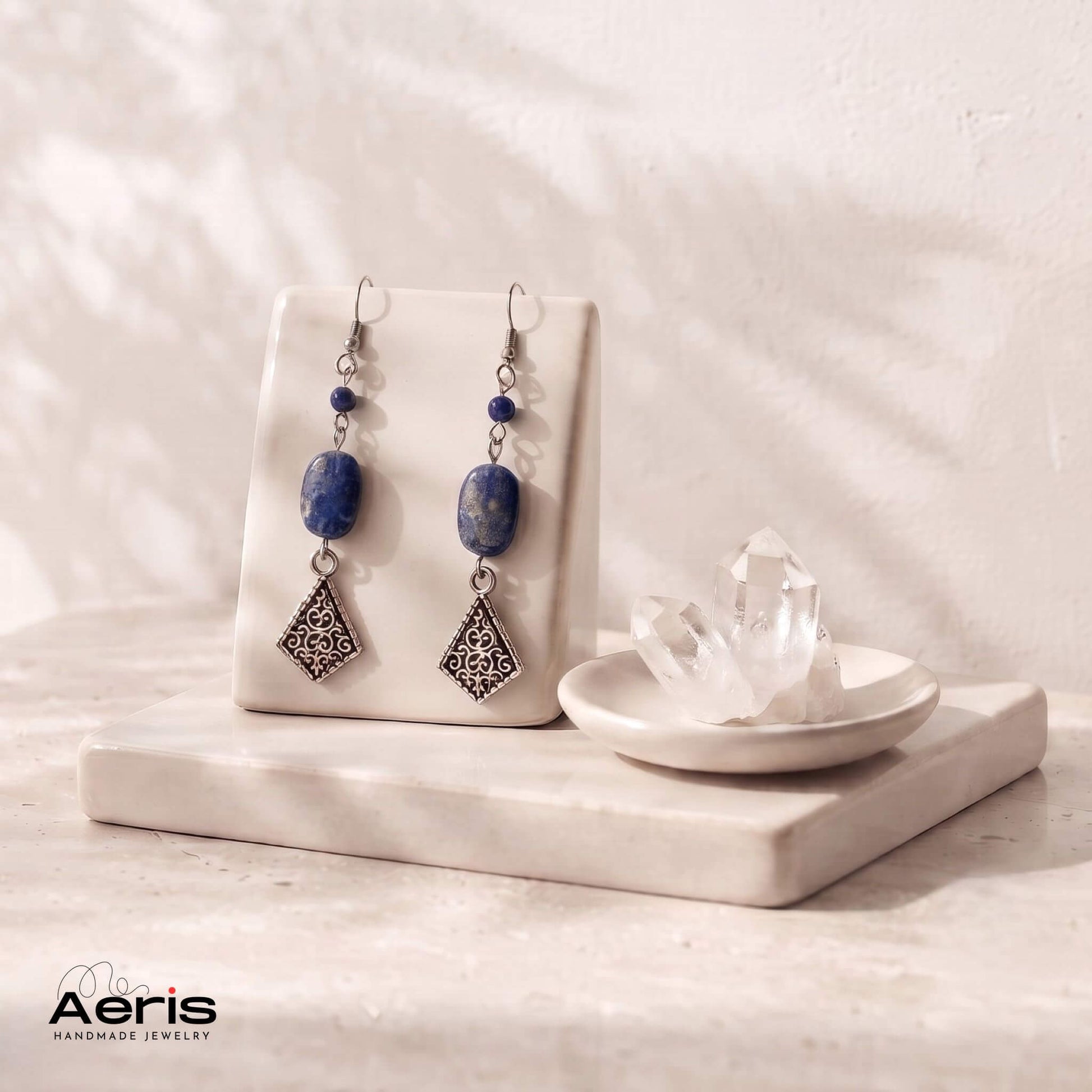 Cercei pendul, lungi, cu lapis lazuli si elemente metalice vintage, prezentati pe suport ceramic