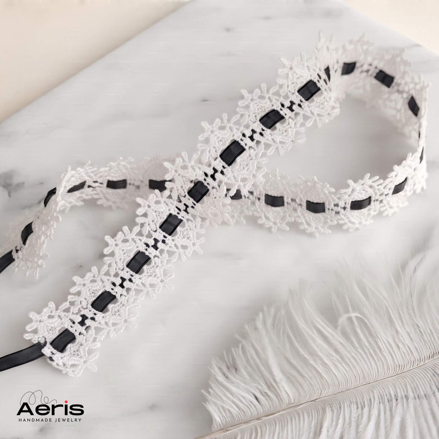 Choker din dantela alba cu panglica neagra, asezat pe o placa de marmura