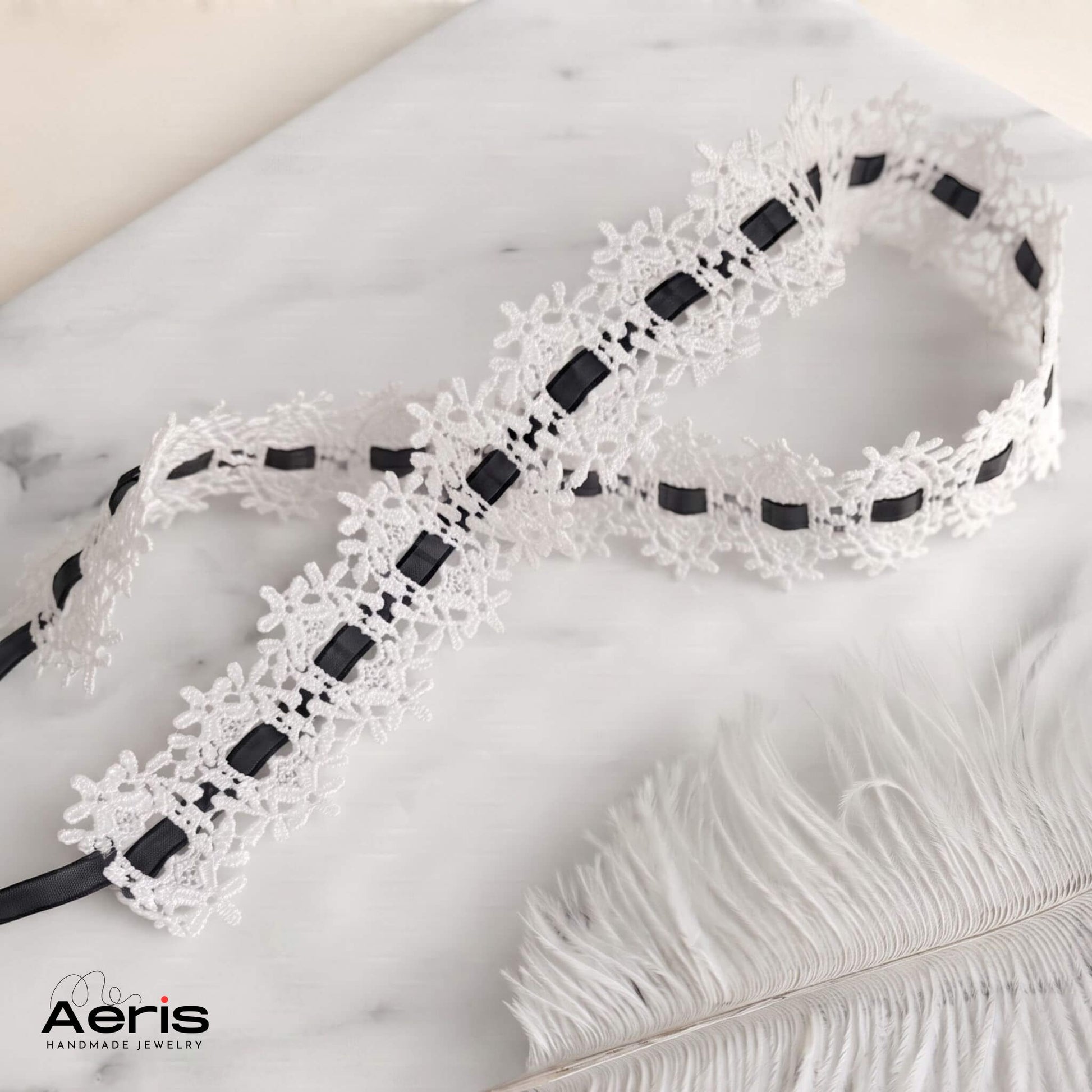 Choker din dantela alba cu panglica neagra, asezat pe o placa de marmura