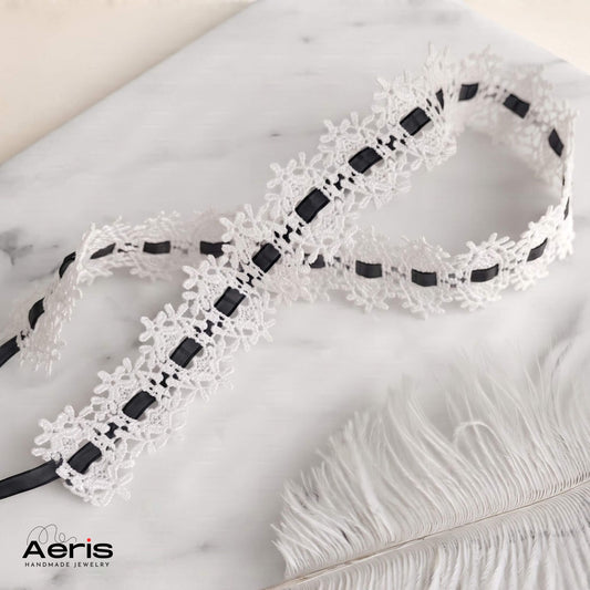 Choker din dantela alba cu panglica neagra, asezat pe o placa de marmura