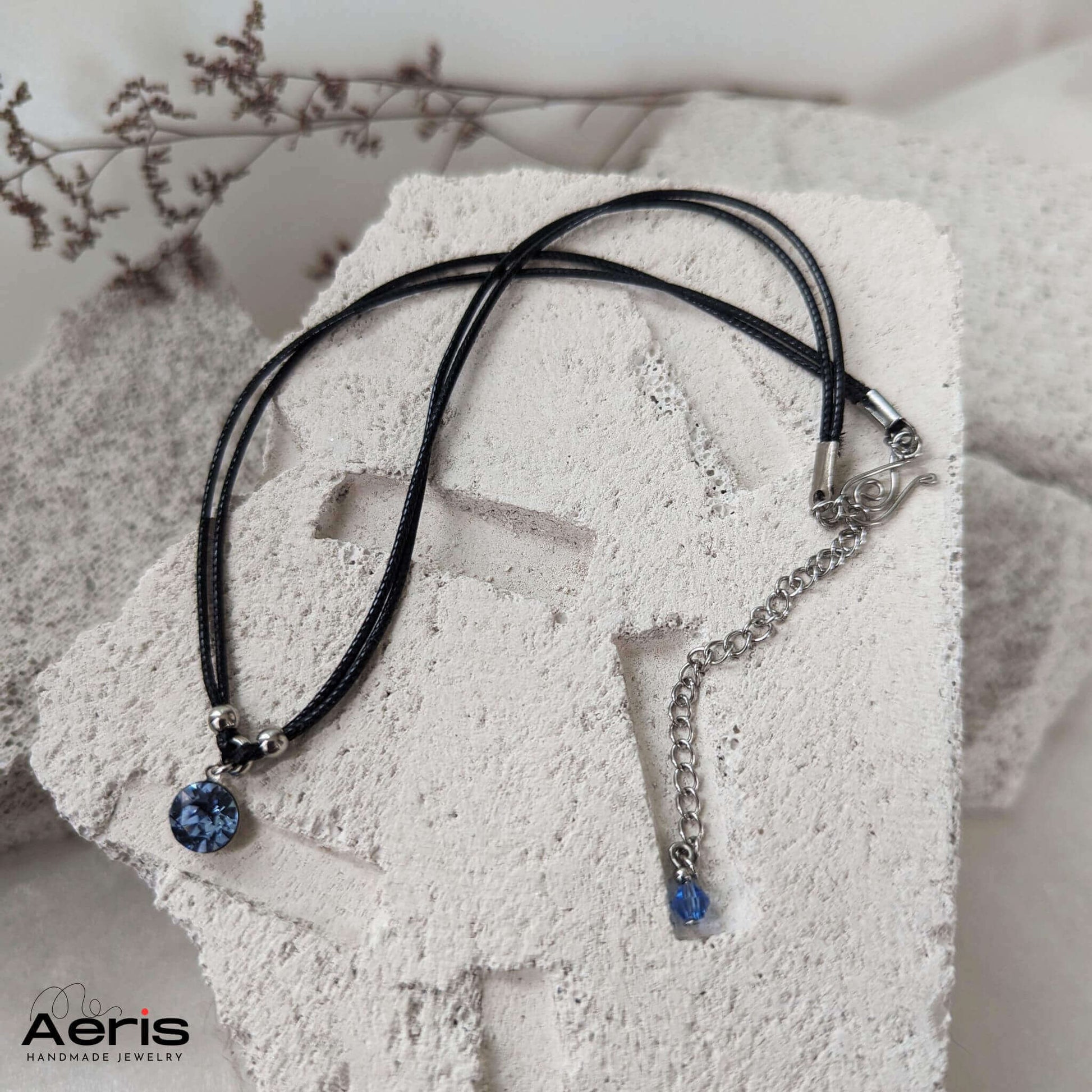 Choker negru minimalist asezat pe o placa din beton