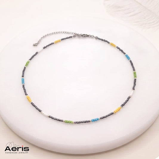 Choker multicolor din margele de nisip, expus pe un soclu din ceramica