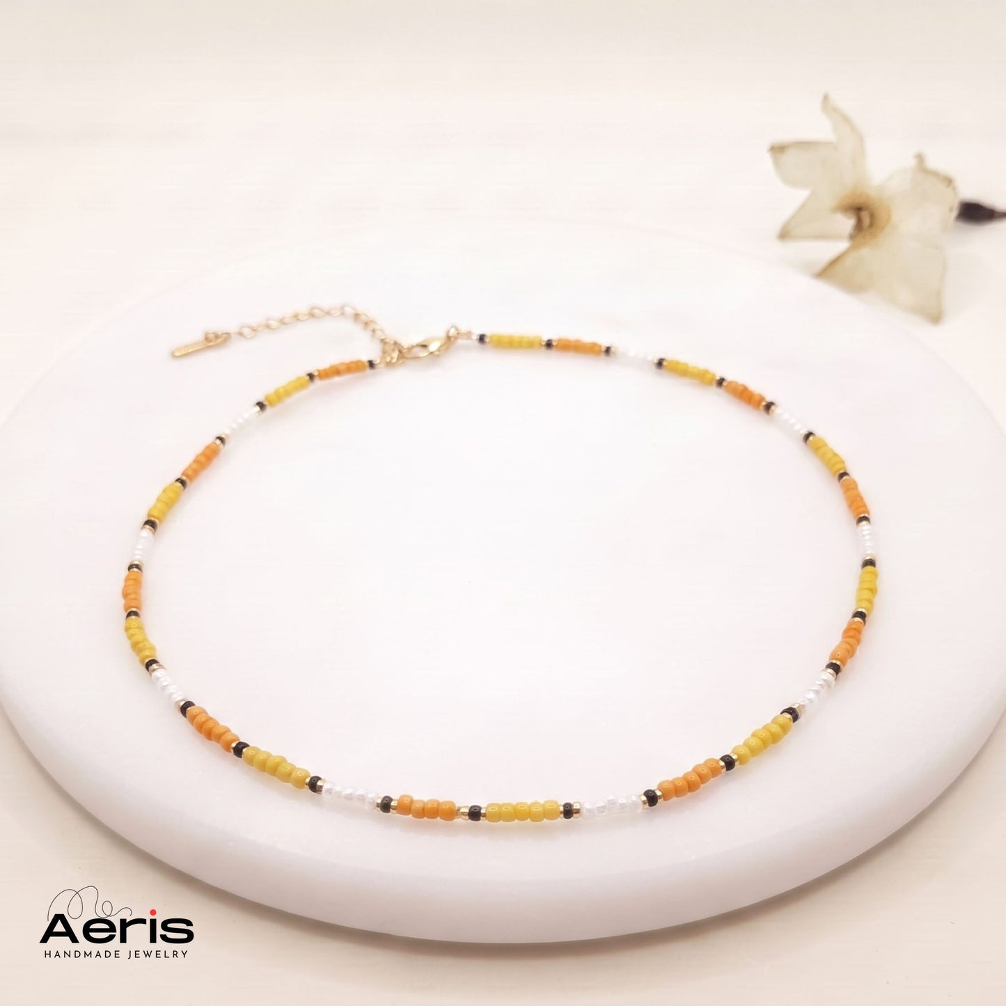Choker handmade in culori de alb, auriu, galben si portocaliu, pezentat pe un disc rotund din ceramica