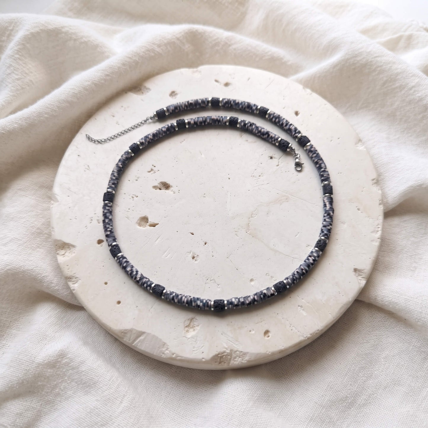 Colier handmade pentru barbati, expus pe un disc din piatra