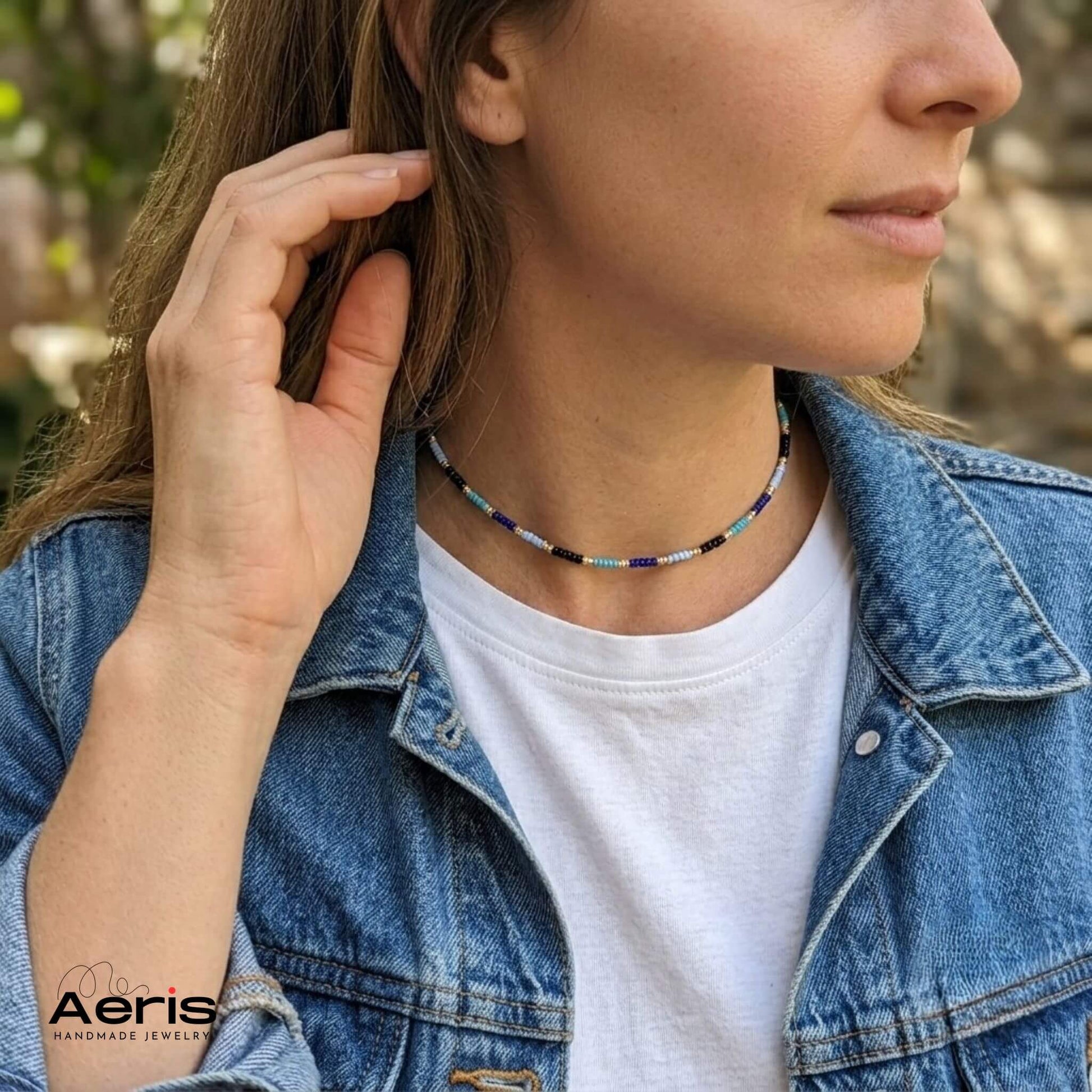 Femeie aranjandu-si parul si purtand chokerul multicolor in nuante de albastru