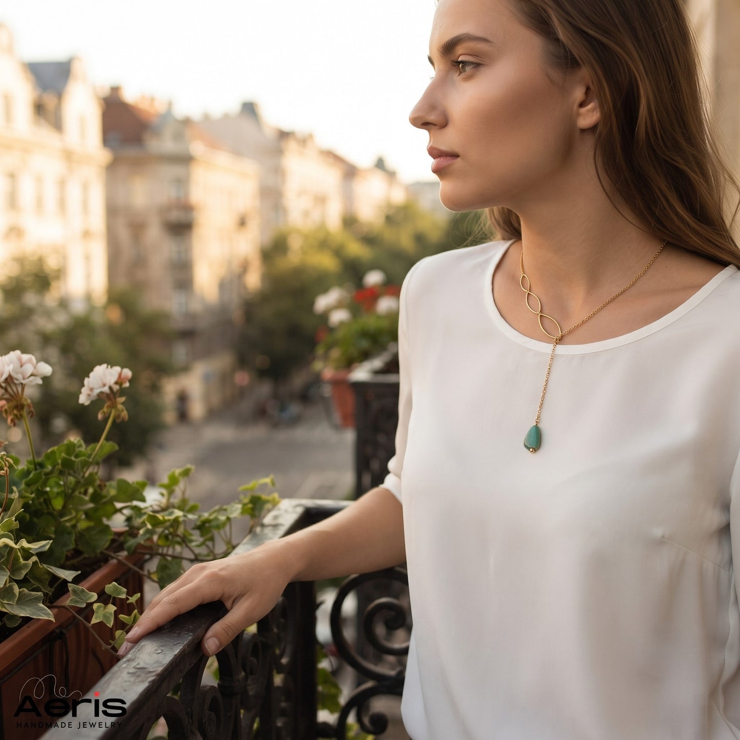 Femeie admirand privelistea din balcon si purtand colierul auriu cu pandantiv din coral albastru