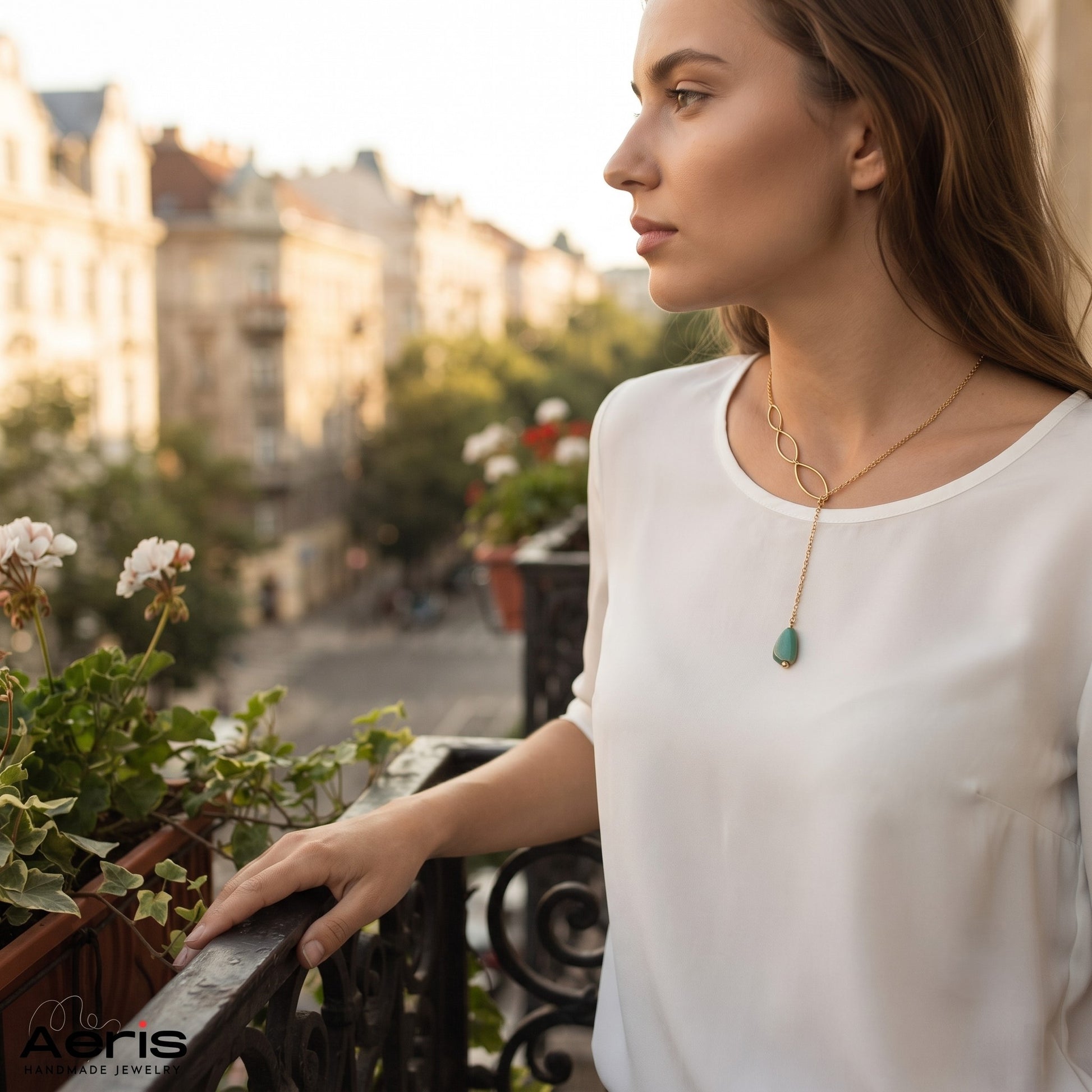 Femeie admirand privelistea din balcon si purtand colierul auriu cu pandantiv din coral albastru