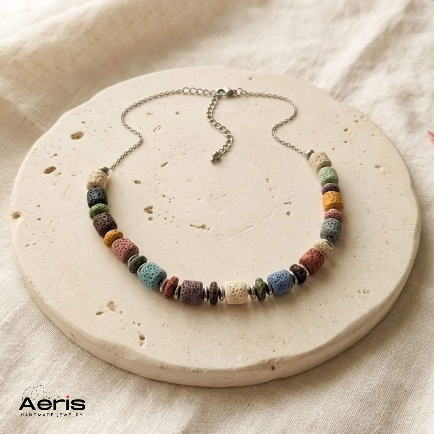 Colier handmade multicolor, prezentat pe un soclu rotund din ceramica mata 