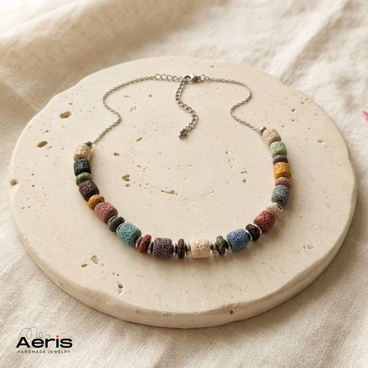 Colier handmade multicolor, prezentat pe un soclu rotund din ceramica mata 