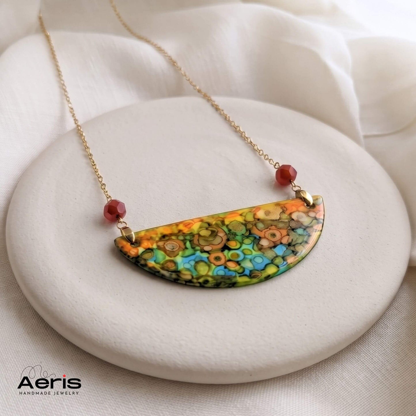 Colier handmade multicolor, expus pe o baza rotunda din ceramica