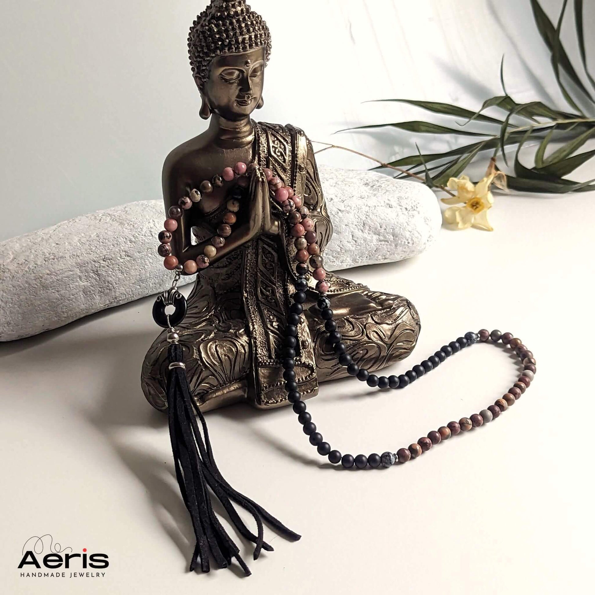 Colier mala cu onix si rodonit, langa o statuie a lui Budha