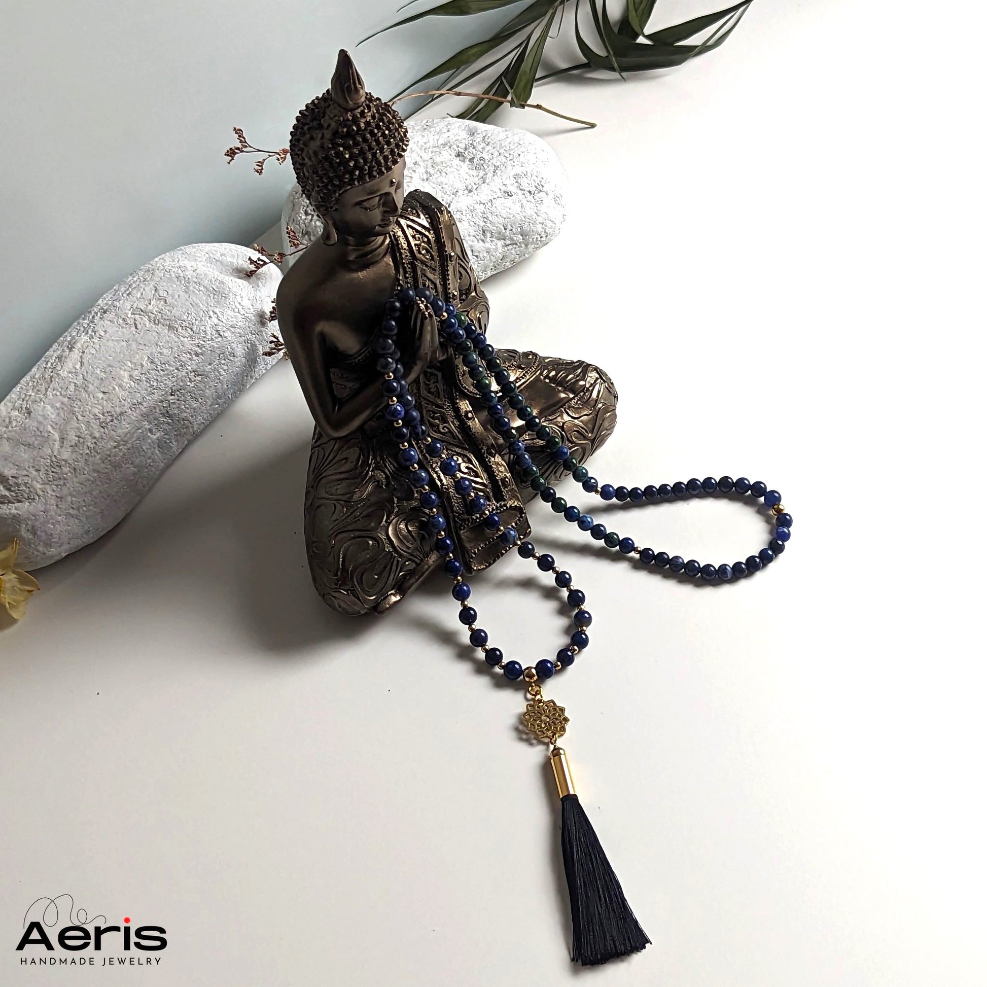 Colier mala cu mandala aurie si ciucure din matase negru, langa statuia lui Buddha