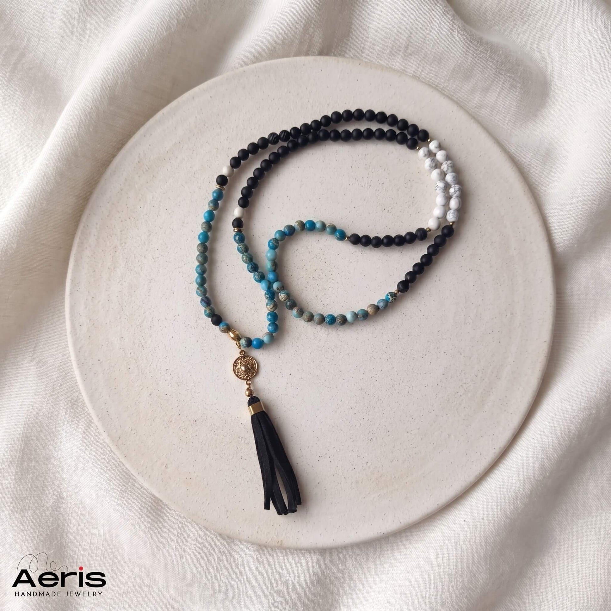 Colier mala cu jasp imperial, howlit si agate negre, prezentat pe un disc de ceramica mata