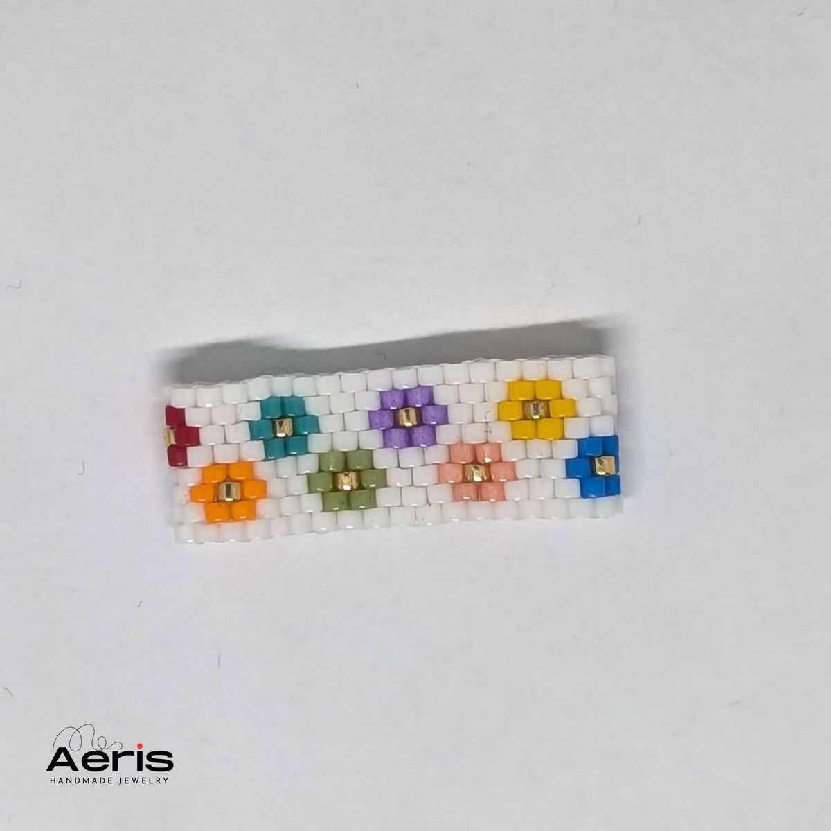Inel vesel cu flori multicolore pe fond alb, realizat din margele Miyuki Delica
