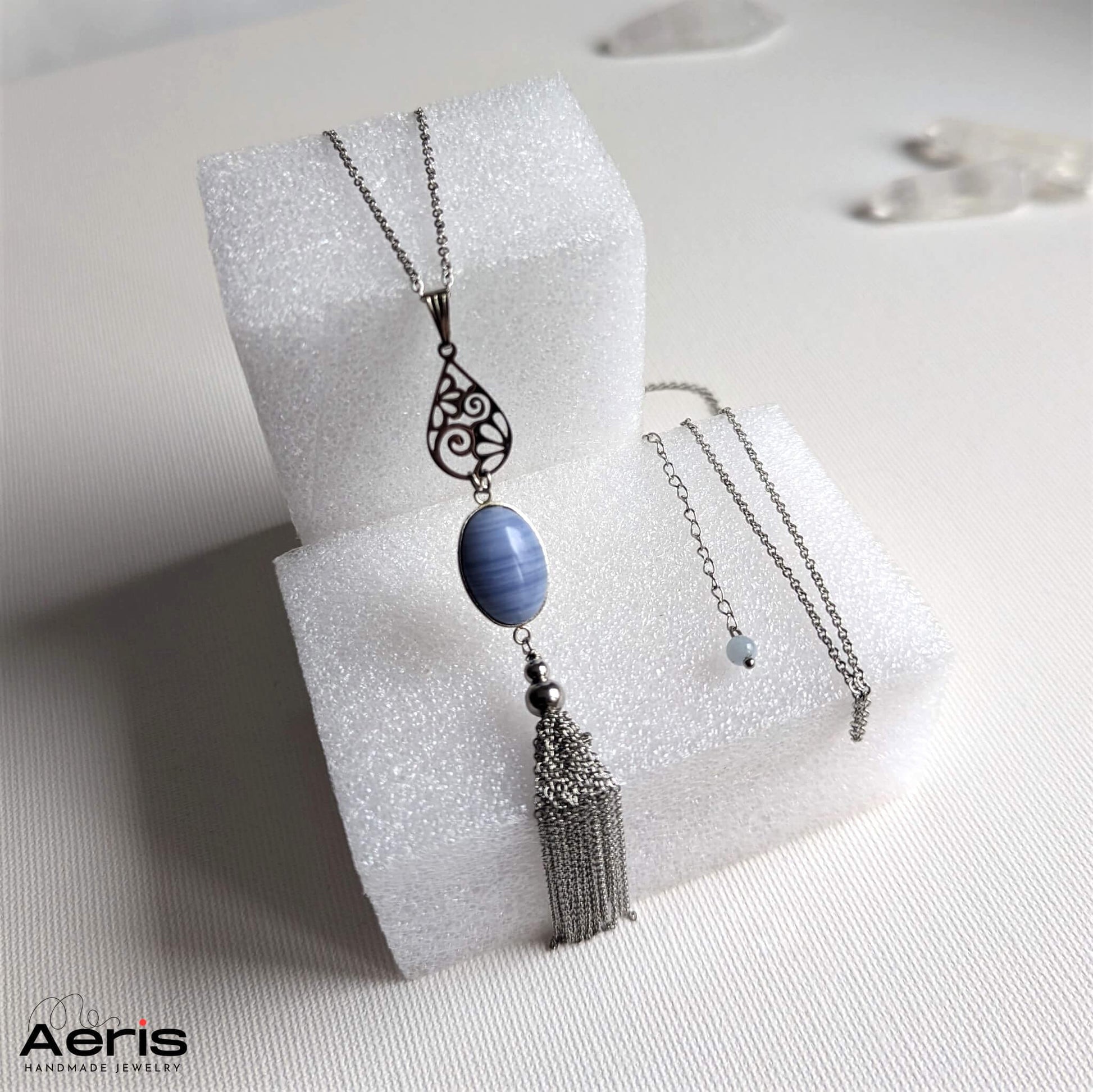 Pandantiv handmade cu piatra bleu si accesorii din inox, prezentat pe suport