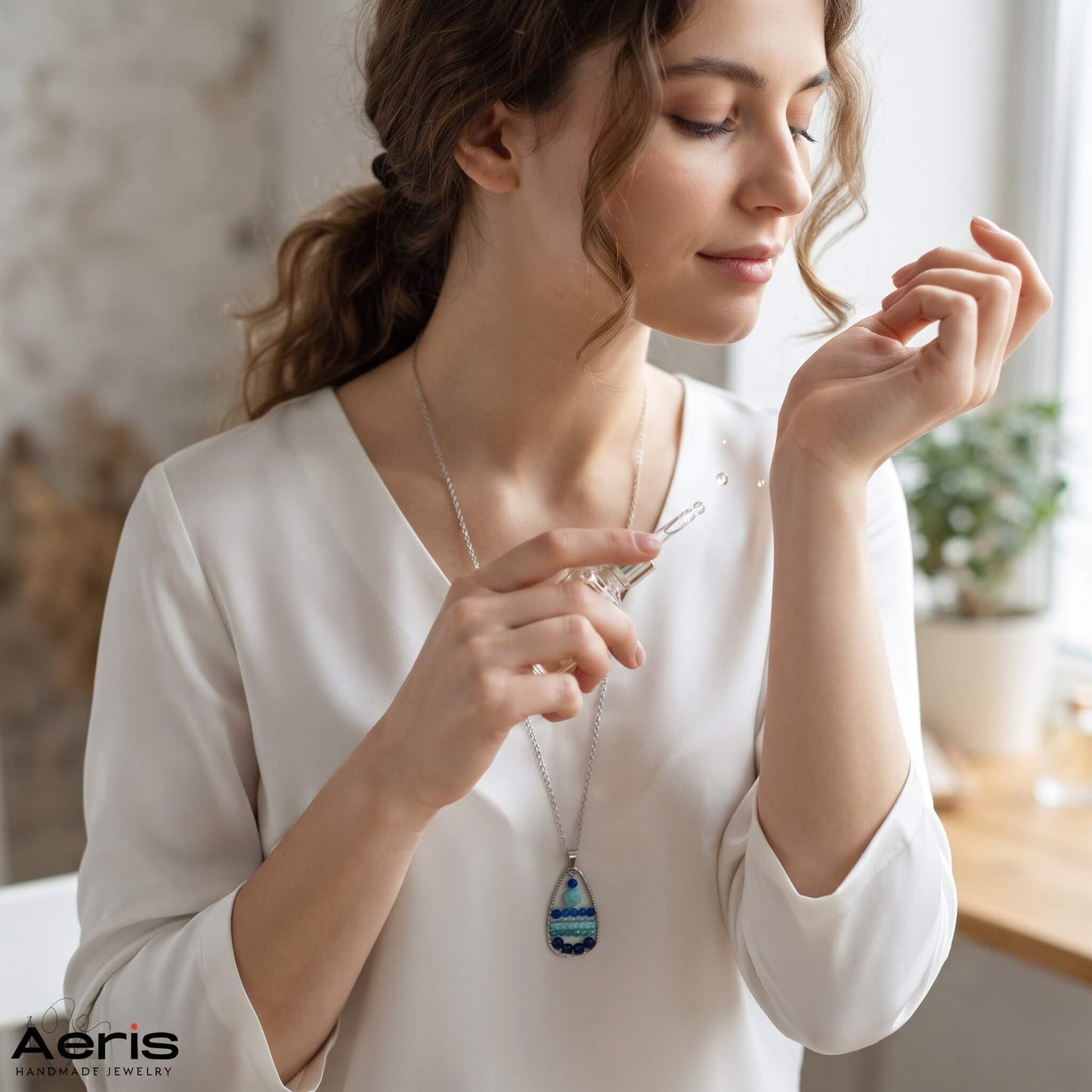 Femeie tanara dandu-se cu parfum si purtand pandantivul model unicat cu cristale naturale