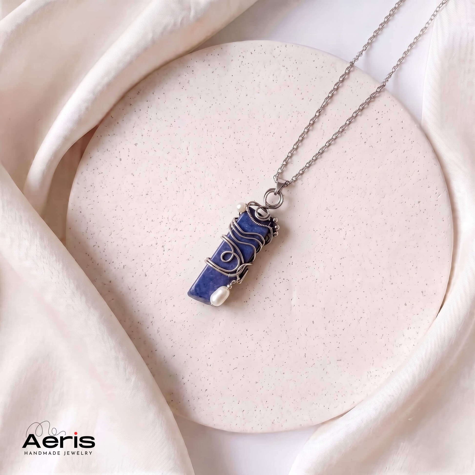 Pandantiv cu lapis lazuli wire wrapped, asezat pe un pad ceramic